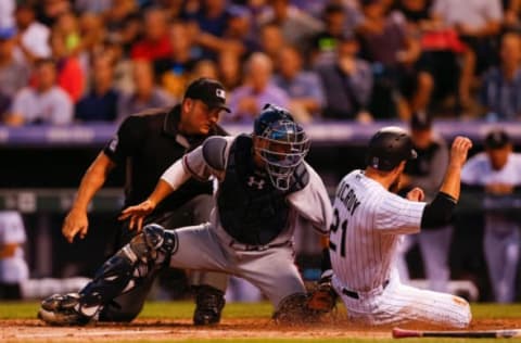 DENVER, CO – AUGUST 16: Jonathan Lucroy #21 of the Colorado Rockies slides safely under the tag of catcher Kurt Suzuki #24 of the Atlanta Braves as home plate umpire Dan Bellino looks on during the third inning at Coors Field on August 16, 2017 in Denver, Colorado. (Photo by Justin Edmonds/Getty Images)