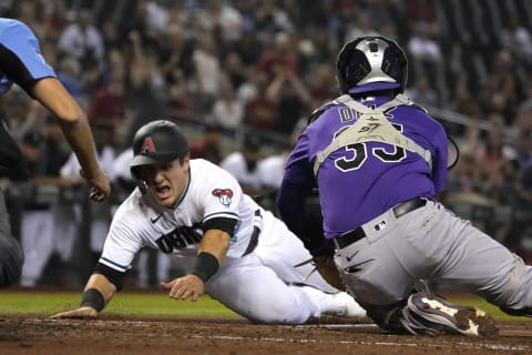 Oct 1, 2021; Phoenix, Arizona, USA; Arizona Diamondbacks catcher Daulton Varsho (12) dives home safely under the tag of Colorado Rockies catcher Elias Diaz (35) in the third inning at Chase Field. Mandatory Credit: Rick Scuteri-USA TODAY Sports