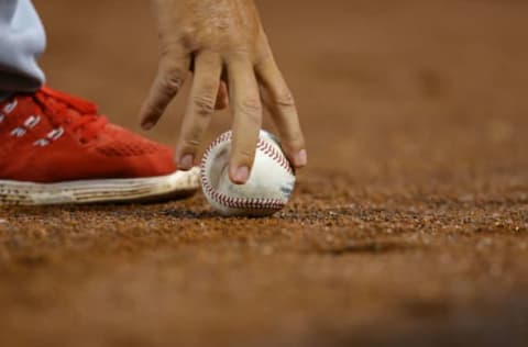 Apr 5, 2017; Cincinnati, OH, USA; Philadelphia Phillies first base coach Mickey Morandini (12) grabs a baseball off the warning track at Great American Ball Park. The Reds won 2-0. Mandatory Credit: Aaron Doster-USA TODAY Sports