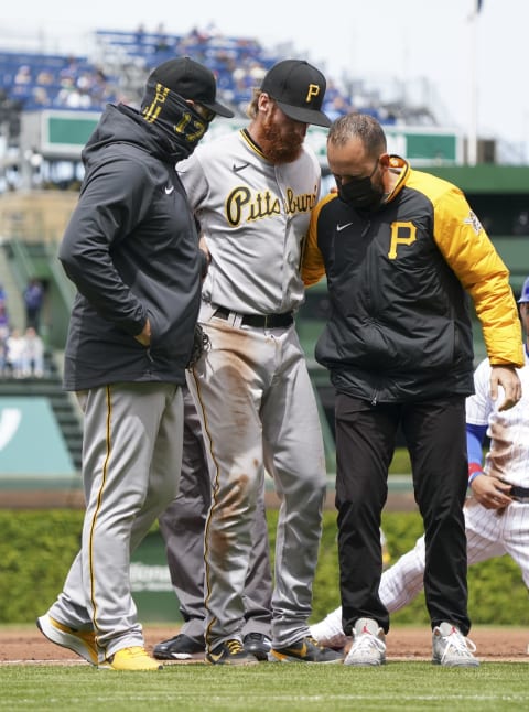 CHICAGO, ILLINOIS – MAY 08: Colin Moran #19 of the Pittsburgh Pirates is led off the field by manager Derek Shelton #17 and a team trainer after an injury during the first inning of a game against the Chicago Cubs at Wrigley Field on May 08, 2021 in Chicago, Illinois. (Photo by Nuccio DiNuzzo/Getty Images)