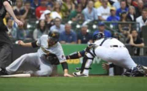 Jun 19, 2017; Milwaukee, WI, USA; Pittsburgh Pirates shortstop Jordy Mercer (10) scores on a base hit by left fielder Adam Frazier (not pictured) before tag by Milwaukee Brewers catcher Manny Pina (9) in the third inning at Miller Park. Mandatory Credit: Benny Sieu-USA TODAY Sports