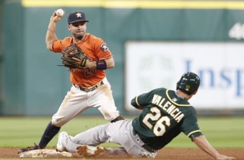 Jun 3, 2016; Houston, TX, USA; Houston Astros second baseman Jose Altuve (27) turns a double play against Oakland Athletics third baseman Danny Valencia (26) in the fourth inning at Minute Maid Park. Mandatory Credit: Thomas B. Shea-USA TODAY Sports