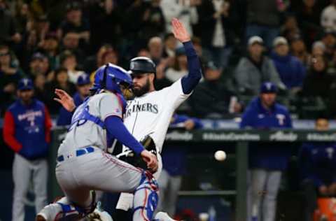 Apr 20, 2022; Seattle, Washington, USA; Seattle Mariners right fielder Jesse Winker (27) slides safely into home to score in front of Texas Rangers catcher Jonah Heim (28) during the fifth inning at T-Mobile Park. Mandatory Credit: Lindsey Wasson-USA TODAY Sports