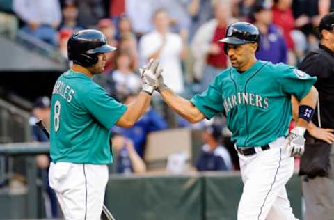 Jul 12, 2013; Seattle, WA, USA; Seattle Mariners designated hitter Kendrys Morales (8) and left fielder Raul Ibanez (28) high five at home plate after Ibanez hit a solo home run against the Los Angeles Angels during the 4th inning at Safeco Field. Mandatory Credit: Steven Bisig-USA TODAY Sports