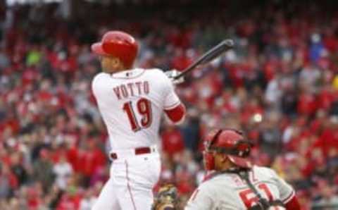 Apr 4, 2016; Cincinnati, OH, USA; Cincinnati Reds first baseman Votto (19) hits a two-run single during the eighth inning against the Philadelphia Phillies at Great American Ball Park. Philadelphia Phillies catcher Ruiz watches at right. The Reds won 6-2. Mandatory Credit: David Kohl-USA TODAY Sports