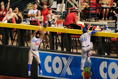 Jul 16, 2016; Phoenix, AZ, USA; Los Angeles Dodgers center fielder Toles (60) leaps to catch a ball hit by Arizona Diamondbacks left fielder Tomas (not pictured) as Dodgers right fielder Puig (66) looks on during the fifth inning at Chase Field. Mandatory Credit: Matt Kartozian-USA TODAY Sports