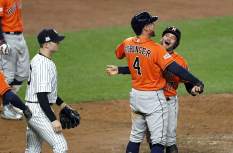 George Springer #4 of the Houston Astros hugs Jose Altuve #27 of the Houston Astros as relief pitcher David Robertson #30 of the New York Yankees walks past (Photo by Paul Bereswill/Getty Images)