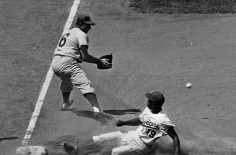 BROOKLYN, NY – 1956: Jim “Junior” Gilliam #19 of the Brooklyn Dodgers slides into third base as Willie Jones #6 of the Philadelphia Phillies waits for the ball during a MLB game in 1956 at Ebbets Field in Brooklyn, New York. (Photo by Herb Scharfman/Sports Imagery/Getty Images)