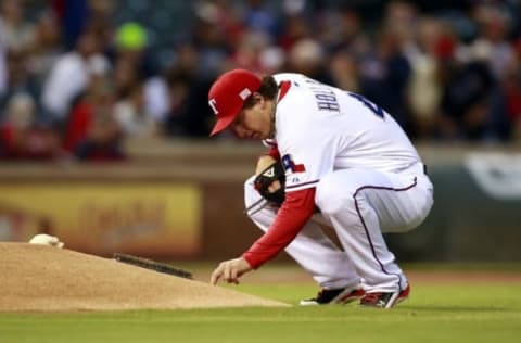 Sep 12, 2014; Arlington, TX, USA; Texas Rangers starting pitcher Derek Holland (45) writes in the dirt behind the mound before he pitches against the Atlanta Braves at Globe Life Park in Arlington. Mandatory Credit: Tim Heitman-USA TODAY Sports