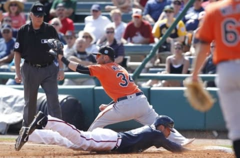 Mar 1, 2016; Lake Buena Vista, FL, USA; First base umpire Gary Cederstrom (left) watches as Atlanta Braves designated hitter Matt Tuiaososopo dives into first base as Baltimore Orioles first baseman Freddie Freeman (34) waits for the ball during the third inning of a spring training baseball game at Champion Stadium. Mandatory Credit: Reinhold Matay-USA TODAY Sports