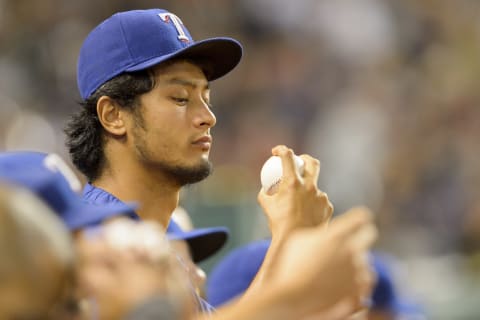 CLEVELAND, OH – AUGUST 1: Pitcher Yu Darvish #11 of the Texas Rangers practices his grip in the dugout during the seventh inning against the Cleveland Indians at Progressive Field on August 1, 2014 in Cleveland, Ohio. (Photo by Jason Miller/Getty Images)