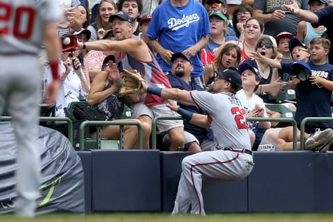 A fan catches a foul ball in front of Austin Riley #27 of the Atlanta Braves. (Photo by Dylan Buell/Getty Images)