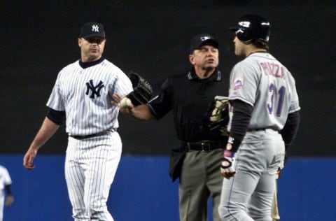 Home plate umpire Charlie Reliford (C) comes between New York Yankees' pitcher Roger Clemens (L) and New York Mets' catcher Mike Piazza after Clemens threw Piazza's broken bat at Piazza as he ran to first base during the first inning of the Second Game of the World Series in New York City 22 October 2000. AFP PHOTO/Gary HIRSHORN/POOL (Photo by GARY HIRSHORN / POOL / AFP) (Photo credit should read GARY HIRSHORN/AFP via Getty Images)