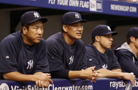 Hiroki Kuroda #18 (L), Masahiro Tanaka #19 (C) and Mark Teixeira #25 (R) look on from the dugout before the start of a game against the Tampa Bay Rays on September 16, 2014 at Tropicana Field in St. Petersburg, Florida. (Photo by Brian Blanco/Getty Images)