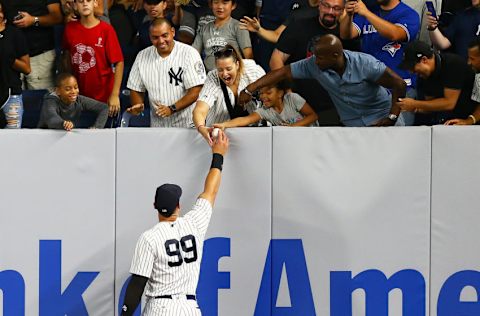 NEW YORK, NY - SEPTEMBER 14: Aaron Judge #99 of the New York Yankees gives a fan a baseball while warming up in the eighth inning for the first time after being activated from the disable list earlier in the day against the Toronto Blue Jays at Yankee Stadium on September 14, 2018 in the Bronx borough of New York City. (Photo by Mike Stobe/Getty Images)