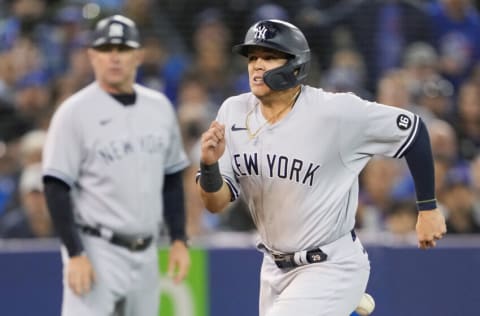 TORONTO, ONTARIO - SEPTEMBER 28: Gio Urshela #29 of the New York Yankees is hit by the throw on his way to scoring against the Toronto Blue Jays in the fifth inning at the Rogers Centre on September 28, 2021 in Toronto, Ontario, Canada. (Photo by Mark Blinch/Getty Images)