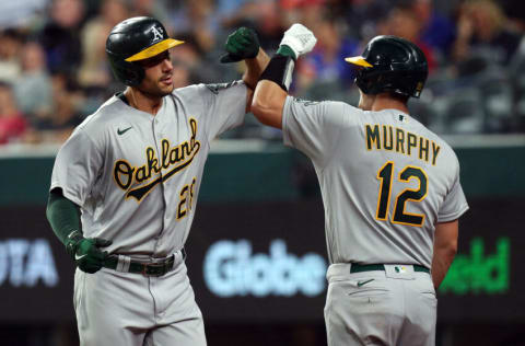 ARLINGTON, TEXAS - AUGUST 14: Matt Olson #28 bumps elbows with Sean Murphy #12 of the Oakland Athletics after a solo home run in the sixth inning against the Texas Rangers at Globe Life Field on August 14, 2021 in Arlington, Texas. (Photo by Richard Rodriguez/Getty Images)