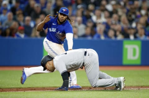 TORONTO, ON - MAY 03: Marwin Gonzalez #14 of the New York Yankees slips as he is chased in a rundown by Vladimir Guerrero Jr. #27 of the Toronto Blue Jays along the third base line in the seventh inning of their MLB game at Rogers Centre on May 3, 2022 in Toronto, Canada. (Photo by Cole Burston/Getty Images)