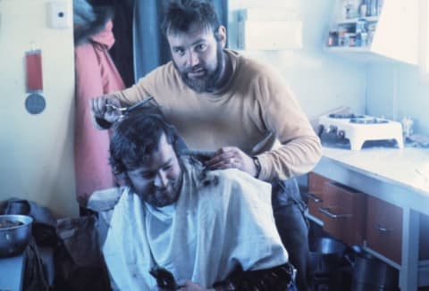 In this photo from the 1970s, a barber experiments on a client at Antarctica New Zealand's Vanda research station.