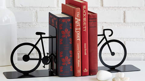 Two bicycle-shaped book ends with four hardcover books between them