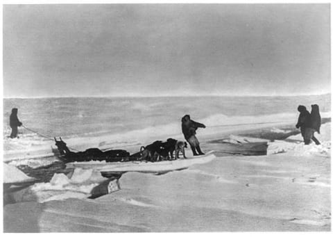 Members of Peary's expedition cross a lead of open water by using an ice floe as a raft.