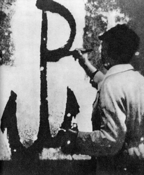 The symbol of the Polish resistance being painted on a wall in German-occupied Poland.